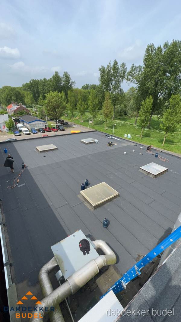 Dakdekker aan het werk op groot plat dak met bitumen in Budel