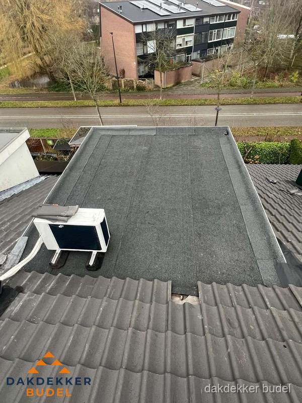 Plat dak inspectie met bitumen bedekking naast schuin pannendak in Budel