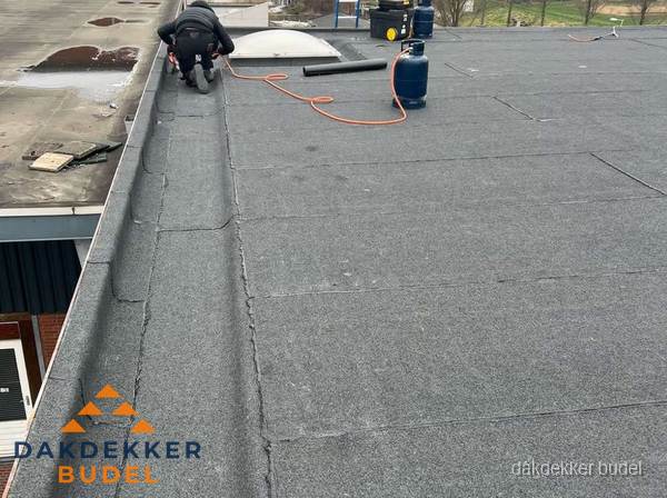 Dakdekker repareert bitumen dakbedekking op groot plat dak in Budel