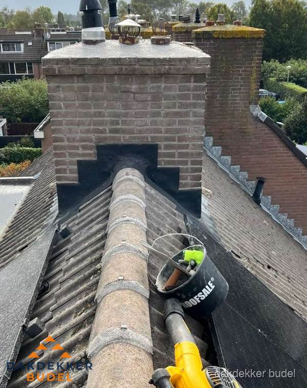 Schoorsteen met loodaansluiting en nokvorst op pannendak in Budel