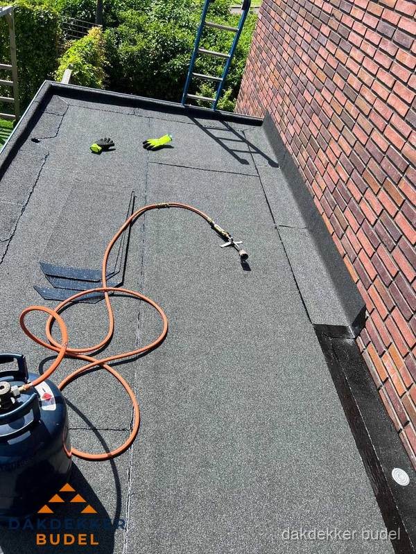 Plat dak met bitumen en brandgereedschap van dakdekkersbedrijf in Budel