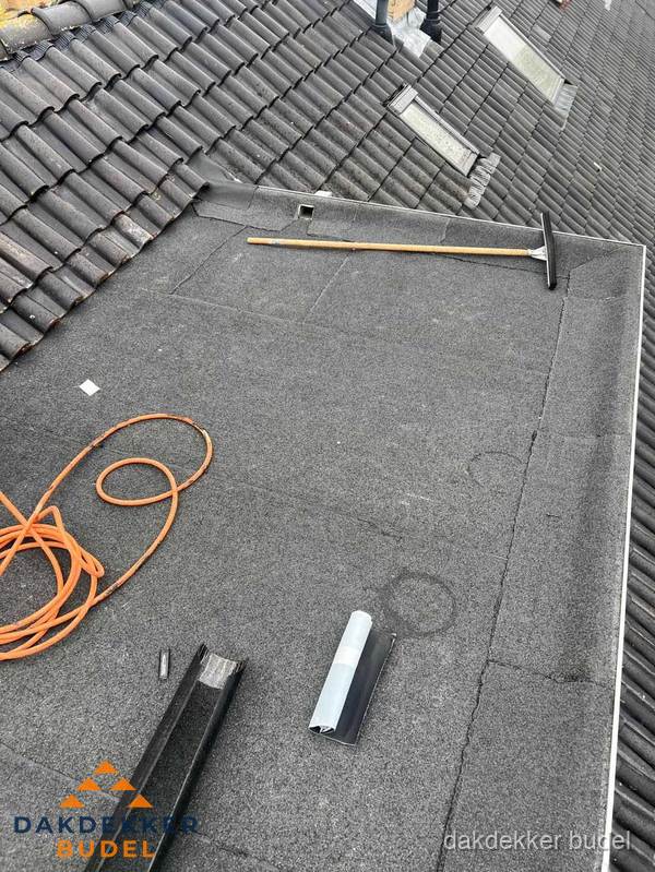 Plat dak reparatie met gereedschap en loodstroken in Budel