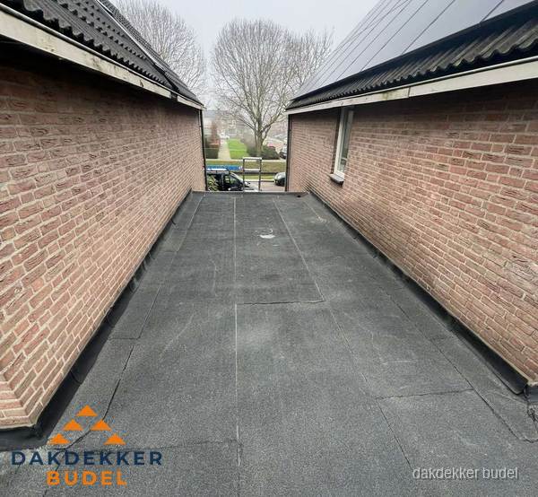 Plat dak met bitumen dakbedekking tussen bakstenen muren in Budel Plat dak met bitumen dakbedekking tussen bakstenen muren in Budel